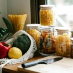 Cozinha organizada com potes herméticos, frutas e legumes frescos, mostrando como economizar na cozinha