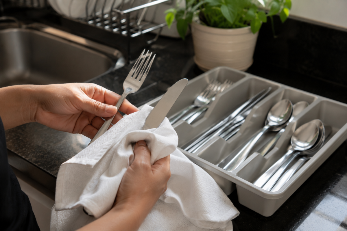  talheres de aço inox sendo secos antes de guardar