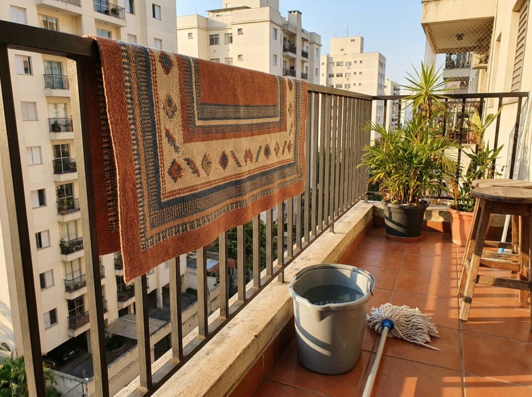 Tapete de cozinha pendurado pra secar enquanto o piso limpo seca ao fundo em apartamento brasileiro
